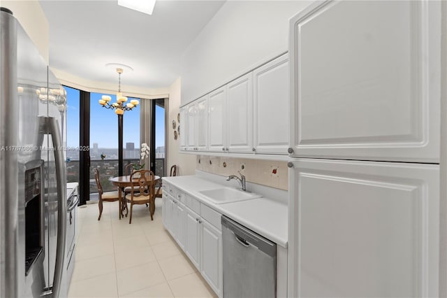 kitchen featuring a sink, a chandelier, stainless steel appliances, light countertops, and white cabinetry
