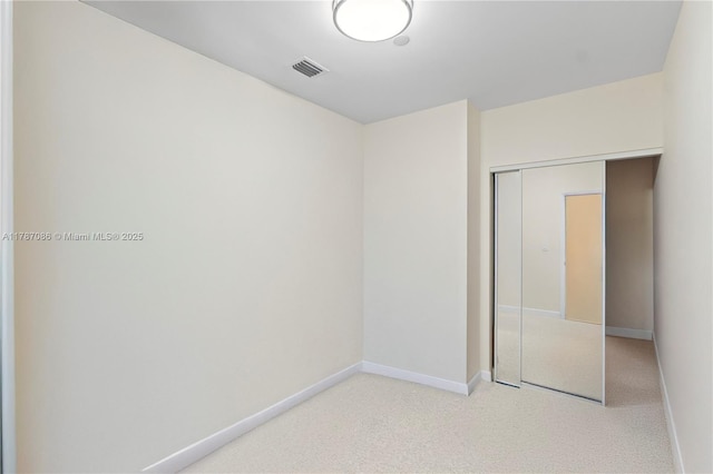 unfurnished bedroom with a closet, visible vents, baseboards, and light colored carpet