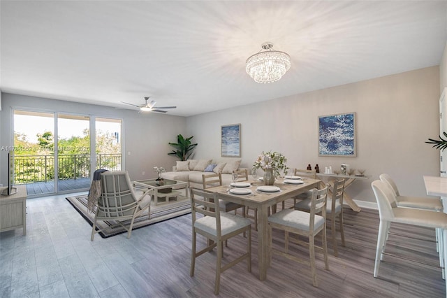 dining space with wood finished floors, a chandelier, baseboards, and a ceiling fan