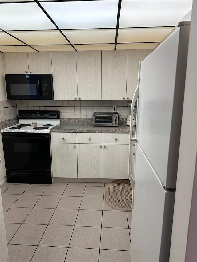 kitchen with a toaster, range with electric stovetop, light tile patterned floors, freestanding refrigerator, and black microwave