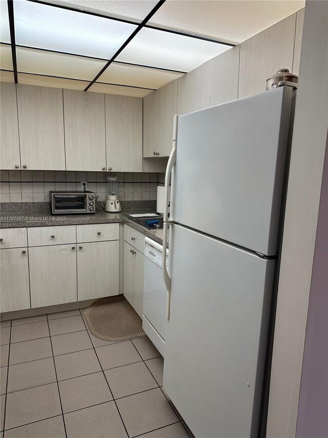 kitchen featuring dark countertops, white appliances, a toaster, and light tile patterned flooring