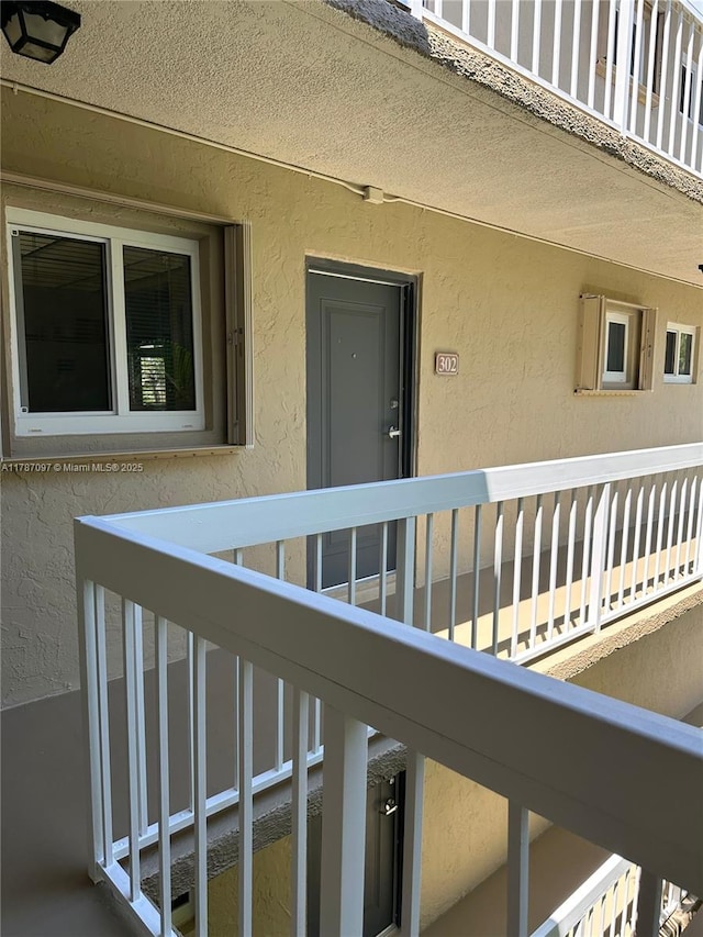 property entrance with a balcony and stucco siding