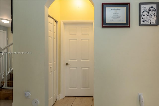 hallway with arched walkways and light tile patterned flooring