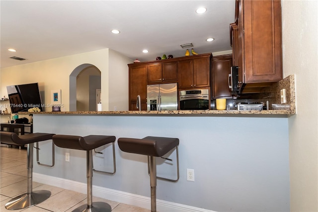 kitchen with stainless steel appliances, a kitchen breakfast bar, visible vents, recessed lighting, and light tile patterned floors