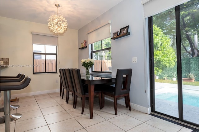 dining area with light tile patterned flooring, baseboards, and a notable chandelier