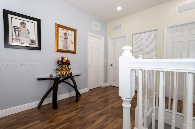 corridor with baseboards, dark wood-style flooring, and visible vents