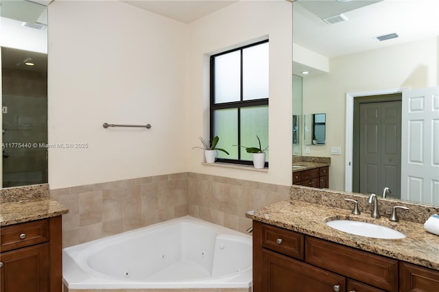 bathroom featuring a jetted tub, visible vents, and vanity