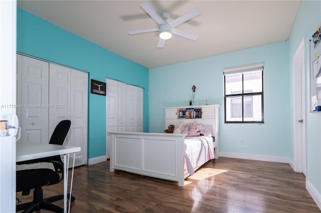 bedroom featuring dark wood finished floors, two closets, baseboards, and ceiling fan