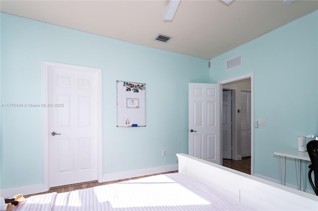 bedroom with wood finished floors, visible vents, a ceiling fan, and baseboards