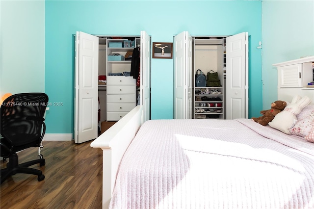 bedroom with two closets and dark wood-type flooring