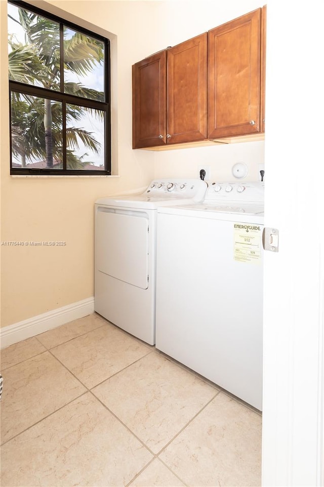 clothes washing area with washing machine and dryer, baseboards, cabinet space, and light tile patterned flooring