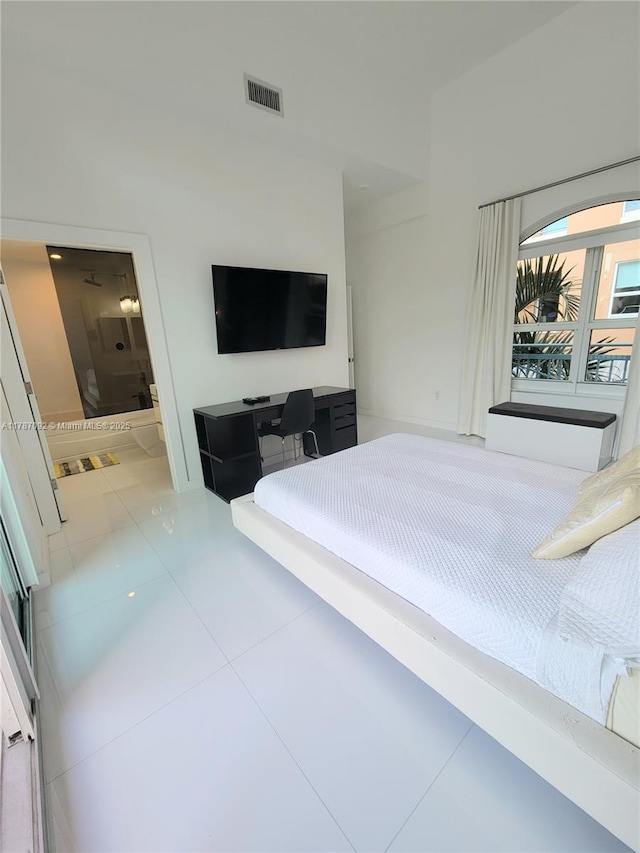 bedroom featuring ensuite bath, tile patterned floors, and visible vents
