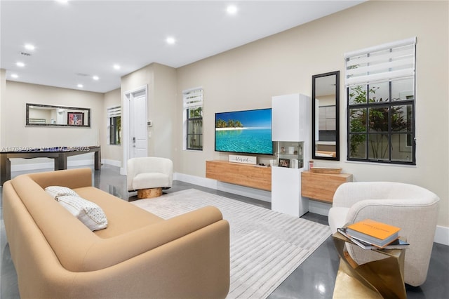 living room with baseboards, recessed lighting, and finished concrete flooring