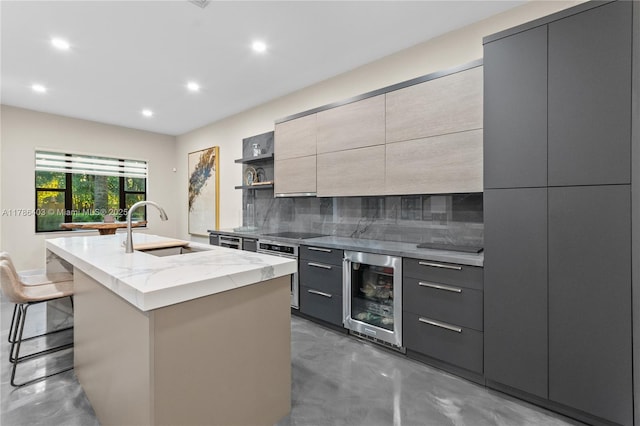 kitchen with a sink, a center island with sink, wine cooler, and modern cabinets