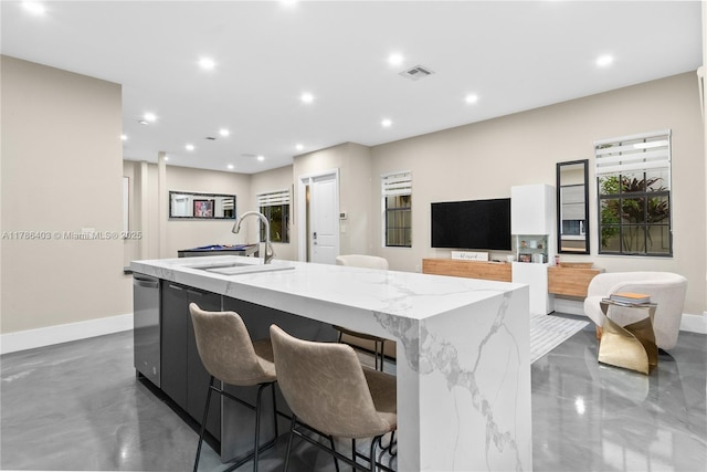 kitchen with a sink, a center island with sink, baseboards, visible vents, and light stone countertops