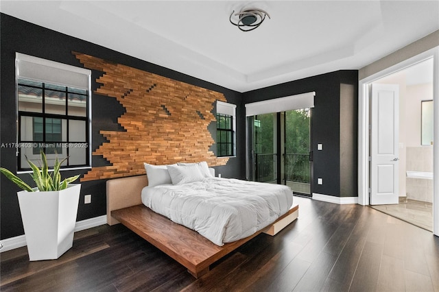 bedroom with wood finished floors, baseboards, access to exterior, and a tray ceiling