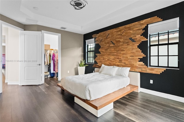 bedroom featuring wood finished floors, a closet, a walk in closet, baseboards, and visible vents