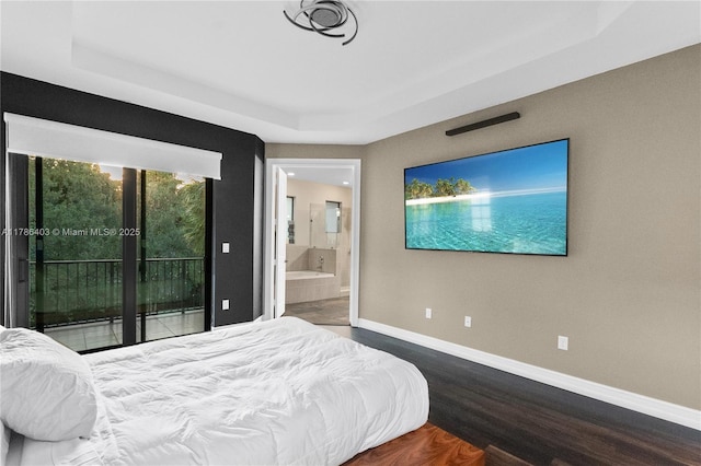 bedroom with a tray ceiling, wood finished floors, access to exterior, and baseboards