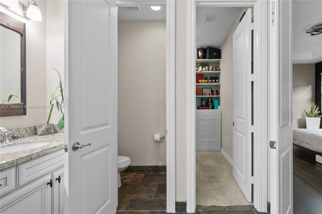 bathroom featuring vanity, toilet, baseboards, and visible vents