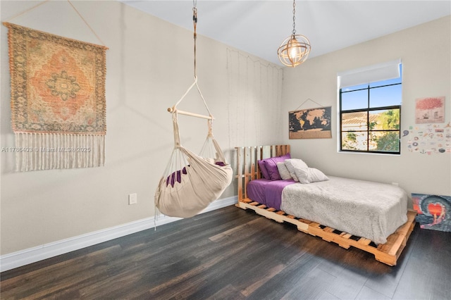 bedroom featuring a chandelier, wood finished floors, and baseboards