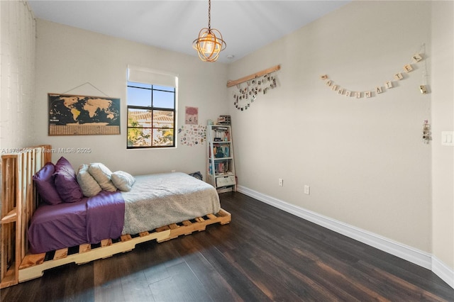 bedroom featuring a chandelier, wood finished floors, and baseboards