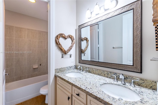 bathroom with toilet, washtub / shower combination, a sink, and double vanity