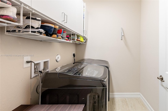 laundry room with baseboards, wood finished floors, washer and dryer, and cabinet space