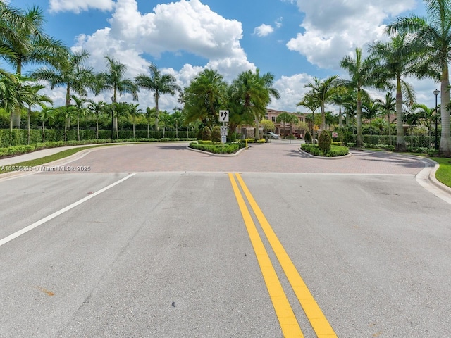 view of street with a gated entry, curbs, sidewalks, and traffic signs