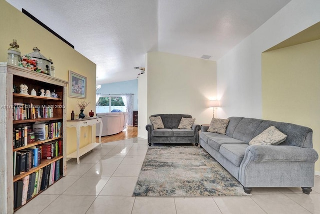 living area featuring light tile patterned flooring, vaulted ceiling, and baseboards
