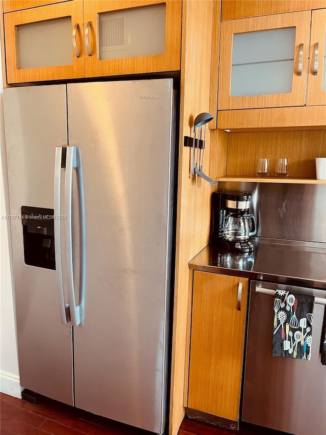 kitchen with brown cabinets, dark wood-style floors, stainless steel appliances, glass insert cabinets, and stainless steel counters
