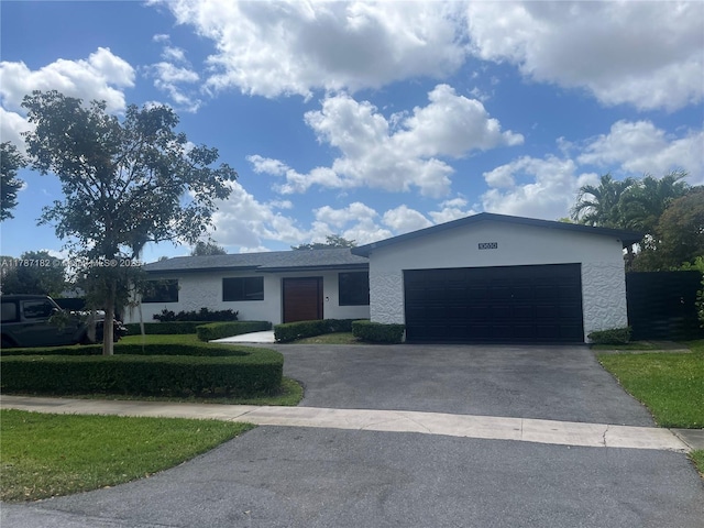 single story home with a garage, stucco siding, driveway, and a front yard