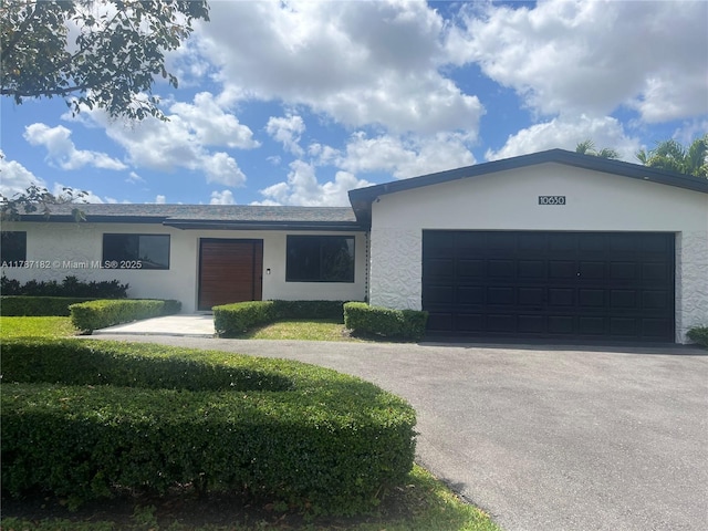 single story home featuring an attached garage, driveway, and stucco siding