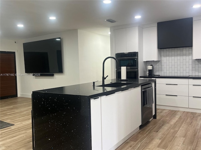 kitchen featuring a sink, decorative backsplash, modern cabinets, and light wood finished floors