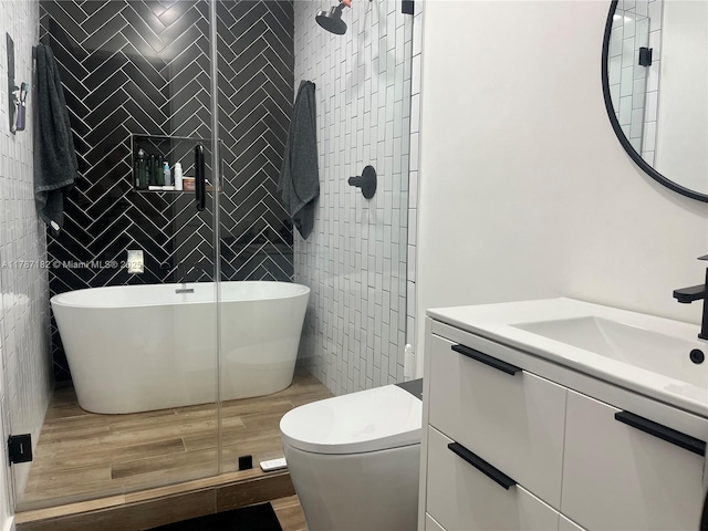 full bath with vanity, wood finished floors, toilet, tile walls, and a stall shower