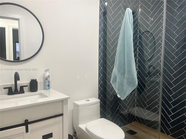 full bathroom with toilet, a tile shower, and vanity