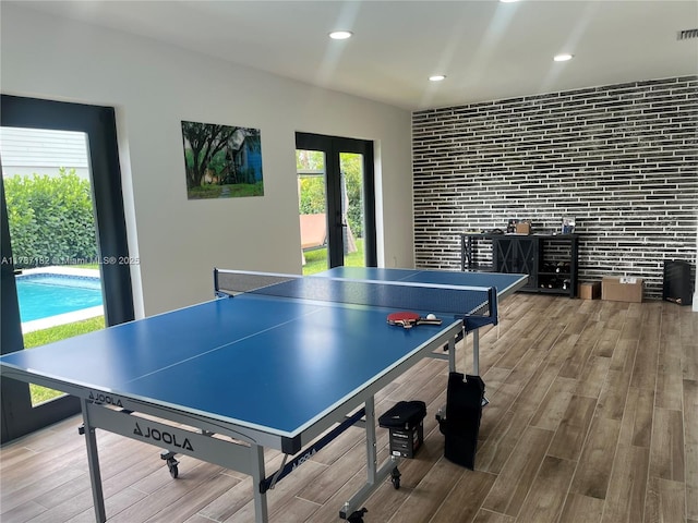 rec room with french doors, brick wall, visible vents, wood finished floors, and recessed lighting