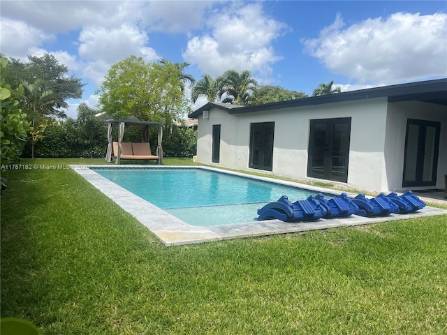 outdoor pool with french doors and a yard