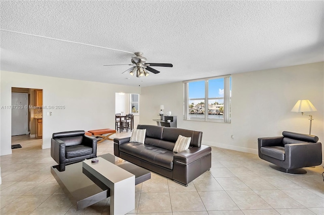 living room featuring a textured ceiling, a ceiling fan, baseboards, and light tile patterned floors