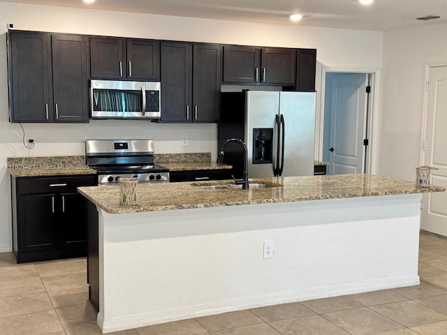 749 SE Karrigan Ter, Port St Lucie, FL 34983 - kitchen with appliances with stainless steel finishes, a sink, a center island with sink, light stone countertops, and recessed lighting