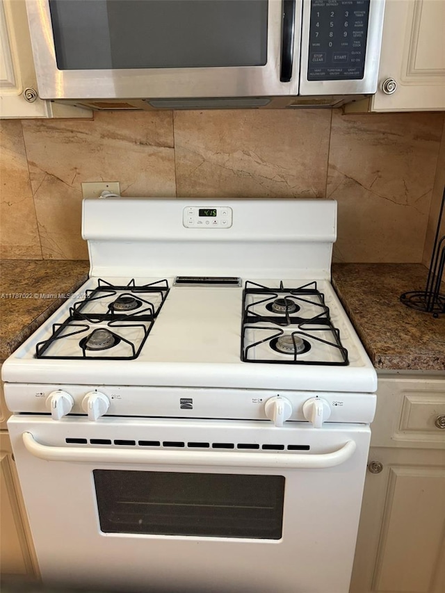 20311 NE 2nd Ave Unit 27, Miami, FL 33179 - kitchen view of white gas stove, stainless steel microwave, tasteful backsplash, and dark countertops