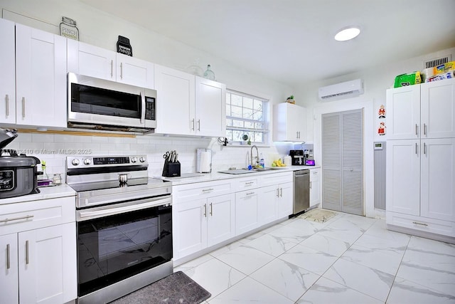 121 E Walnut St, Avon Park, FL 33825 - kitchen with appliances with stainless steel finishes, an AC wall unit, a sink, light marble finish floors, and light countertops