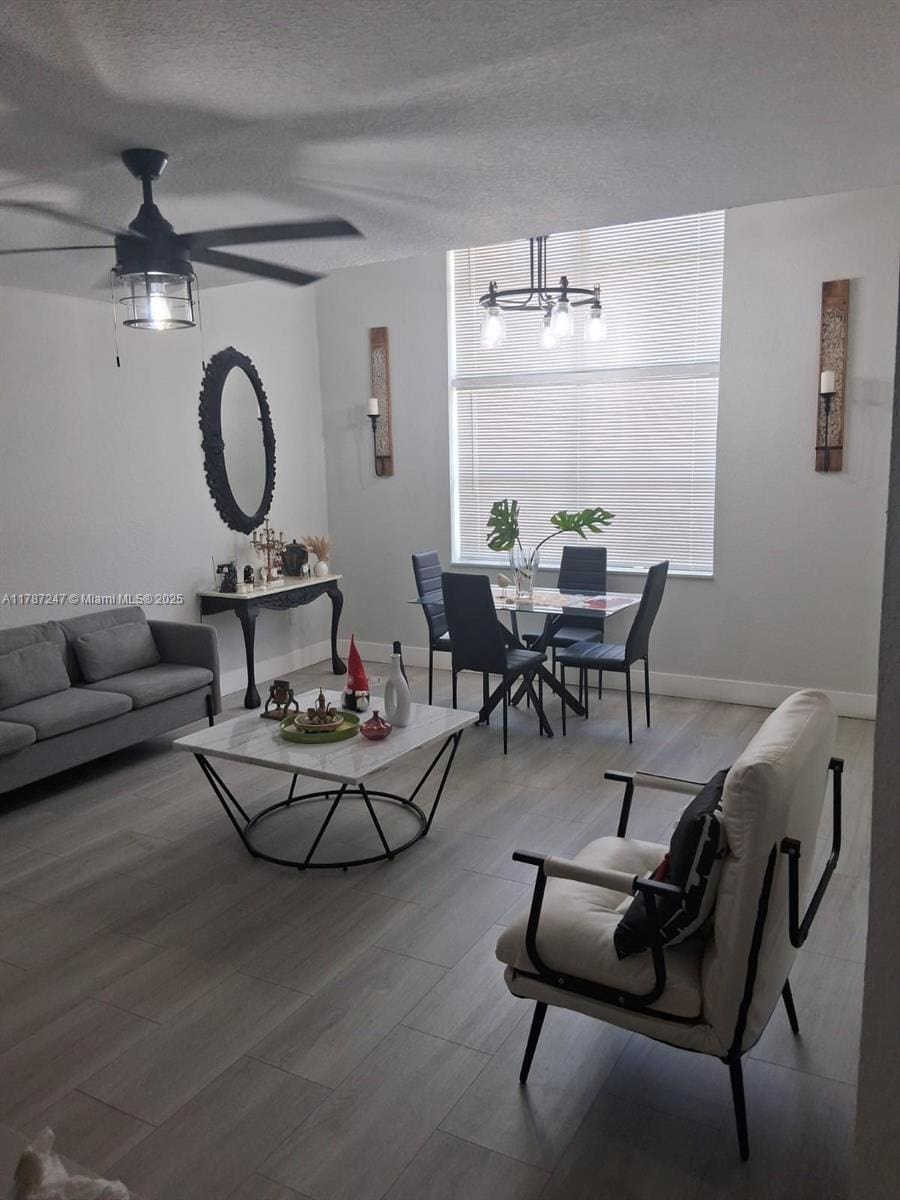 living area with baseboards, wood finished floors, an inviting chandelier, and a textured ceiling