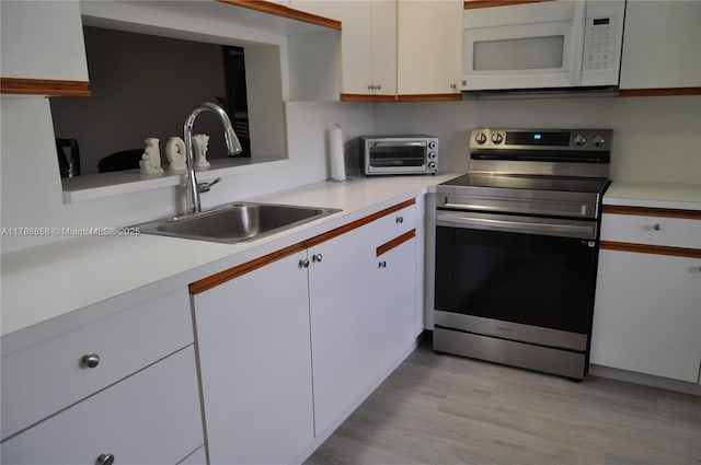 700 SW 128th Ave Unit 106C, Pembroke Pines, FL 33027 - kitchen featuring electric stove, white microwave, a sink, white cabinets, and light countertops