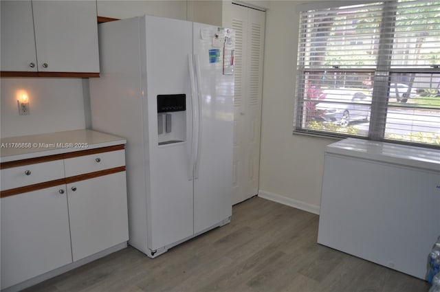 700 SW 128th Ave Unit 106C, Pembroke Pines, FL 33027 - kitchen with white refrigerator with ice dispenser, light wood-style flooring, light countertops, and white cabinetry