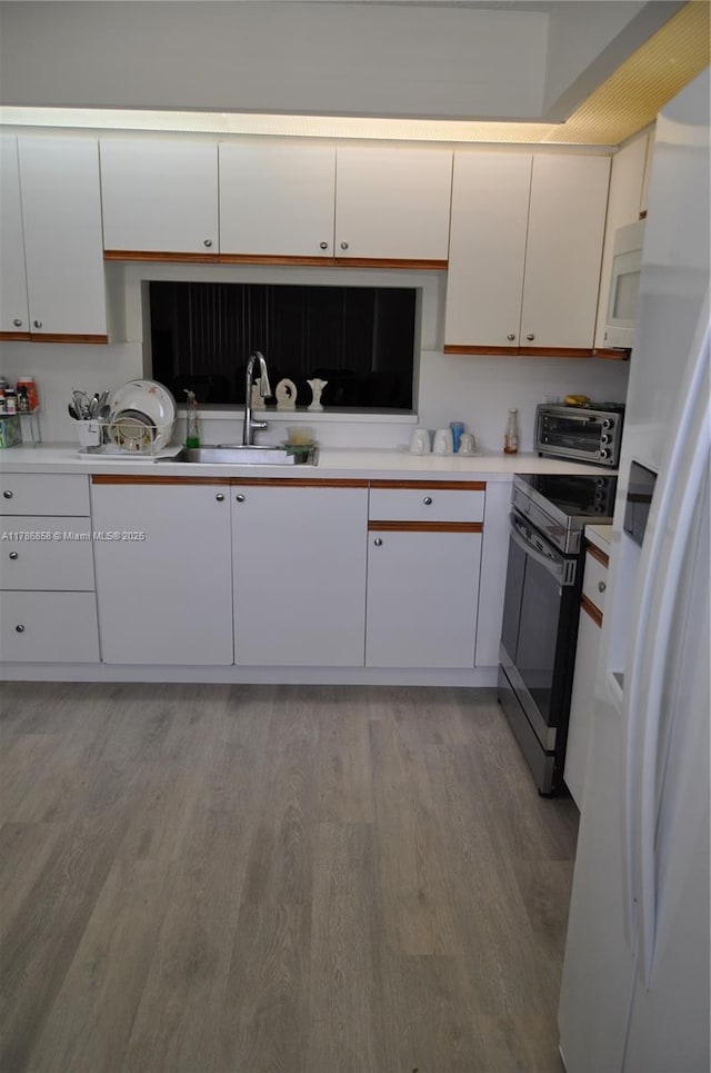 700 SW 128th Ave Unit 106C, Pembroke Pines, FL 33027 - kitchen featuring a sink, white appliances, light wood finished floors, white cabinets, and light countertops