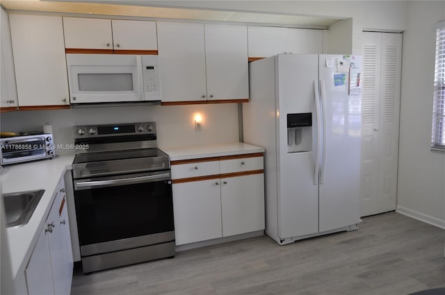 700 SW 128th Ave Unit 106C, Pembroke Pines, FL 33027 - kitchen featuring white appliances, light wood-type flooring, white cabinets, and light countertops
