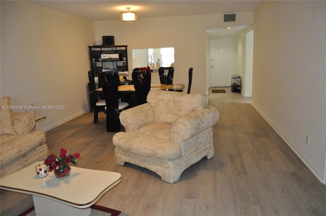 living room featuring baseboards, wood finished floors, and visible vents