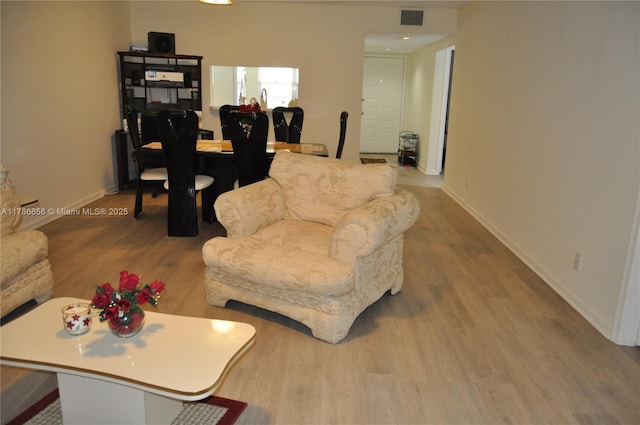living area with visible vents, baseboards, and wood finished floors