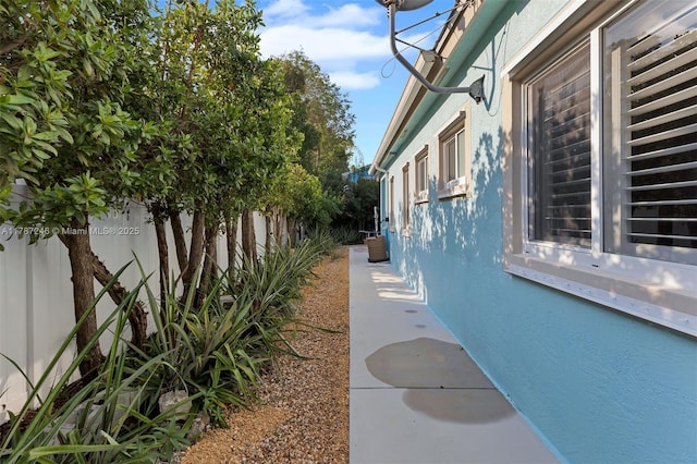 view of side of property featuring stucco siding and fence