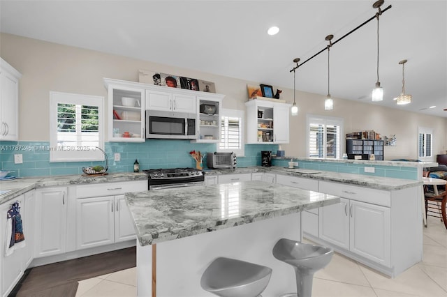 kitchen with a peninsula, open shelves, stainless steel appliances, and a kitchen island